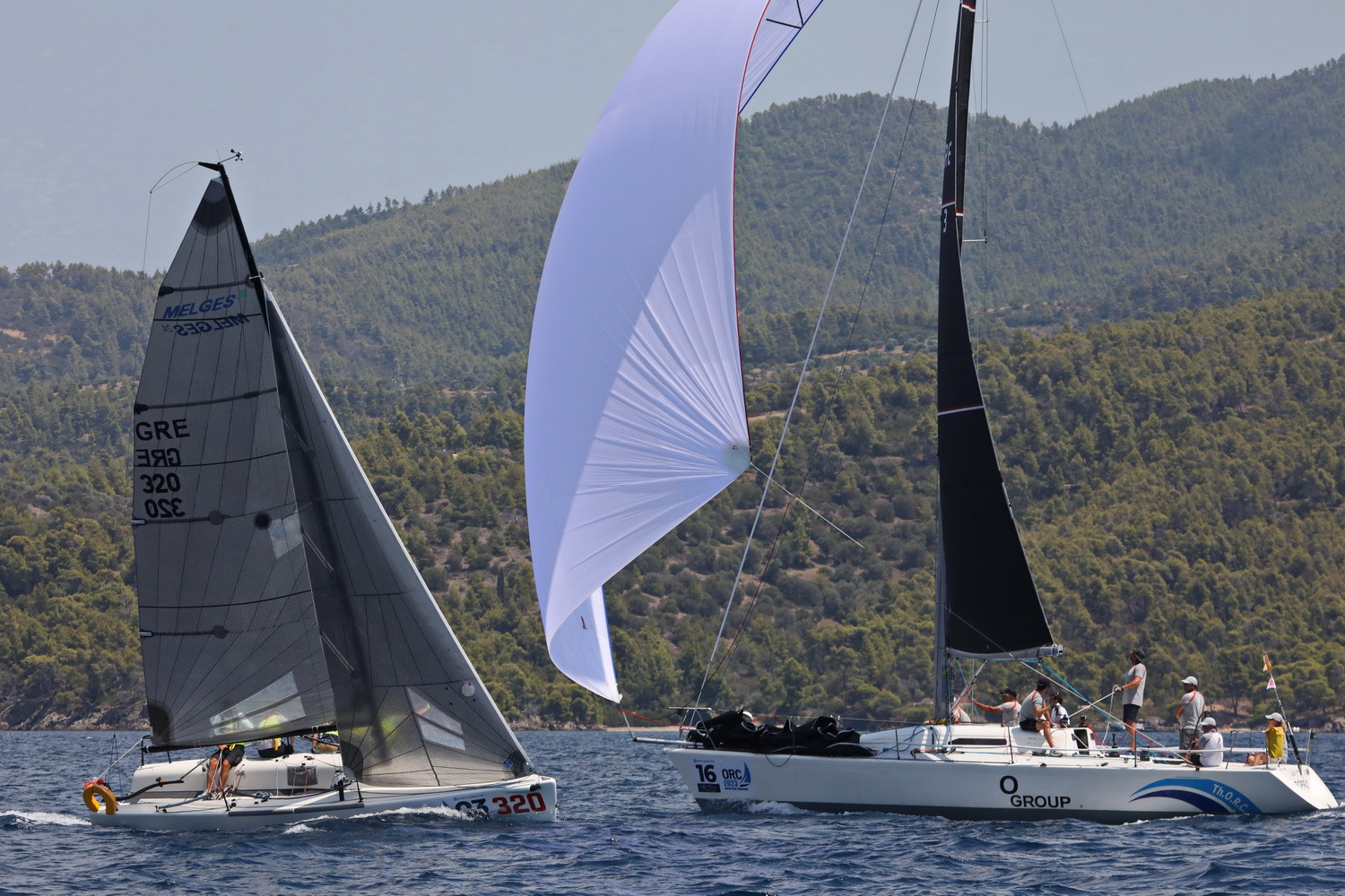 Two sailing boats black main sails and white spinnaker.